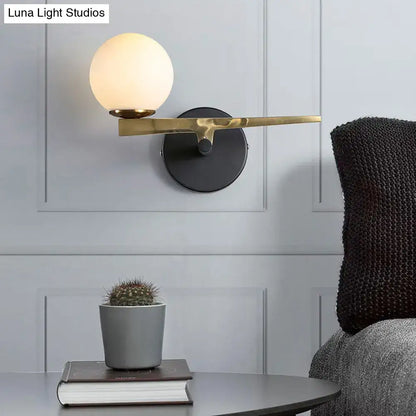 Gold glass sphere wall light with brass arm by Decorbites on black wall mount on Tampa Home & Garden Store