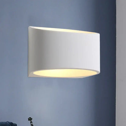 White gypsum hallway wall sconce with cylindrical shade emitting warm downward light on Tampa Home & Garden Store