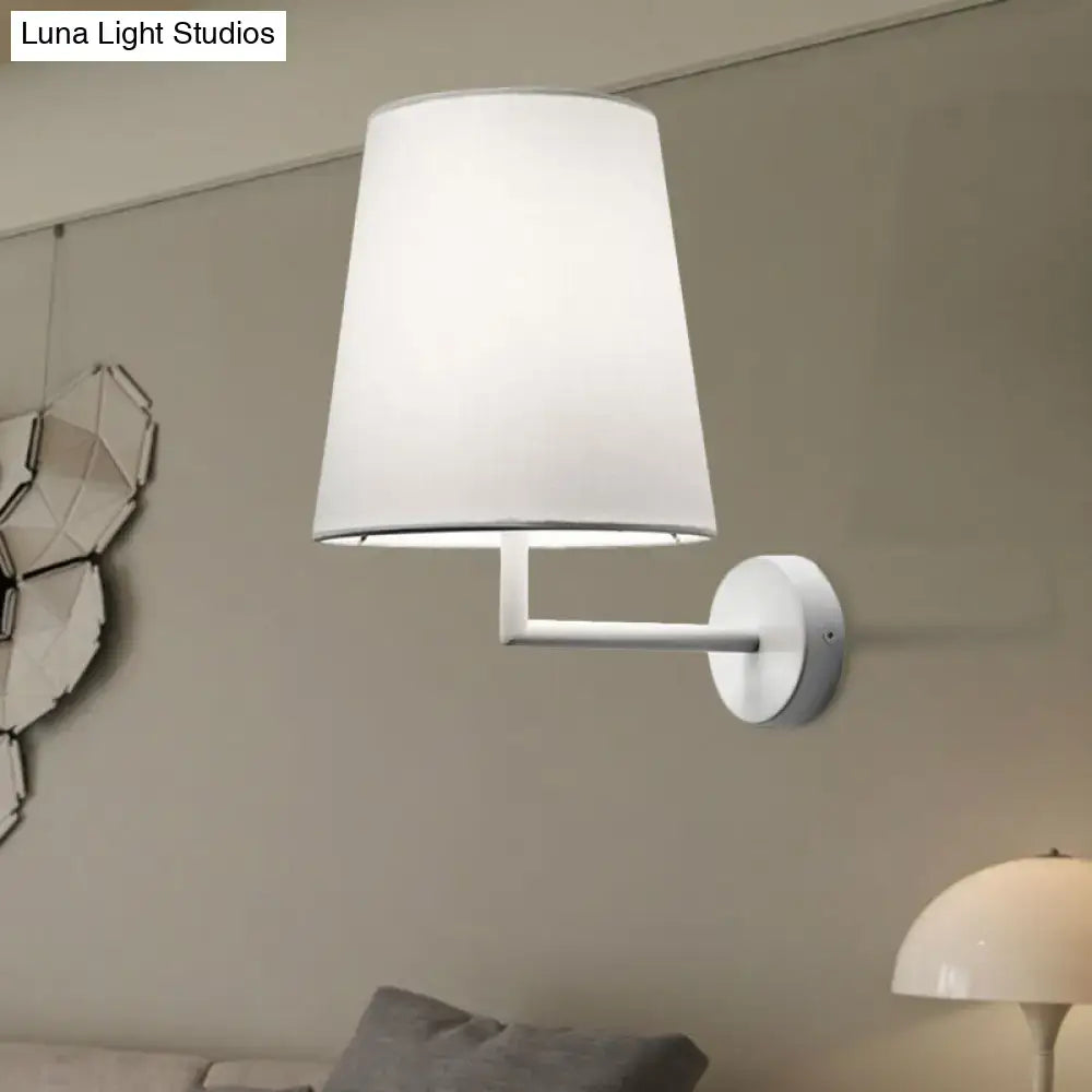 White fabric cone LED wall sconce with slim metal arm mounted on neutral wall on Tampa Home & Garden Store