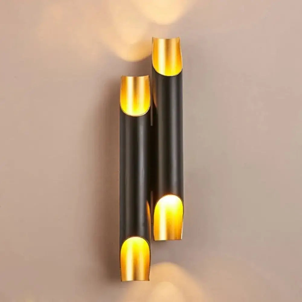 White metal wall sconce with twin cylindrical bodies and gold caps, warm glow on Tampa Home & Garden Store