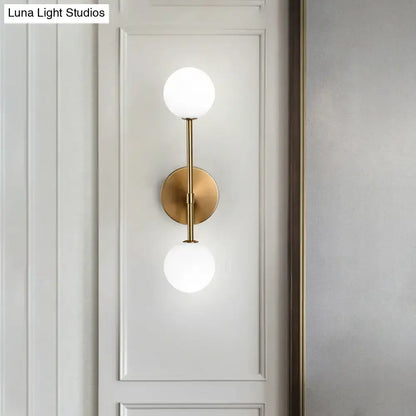 Decorbites gold double globe sconce with brass finish and two white glass globes on Tampa Home & Garden Store