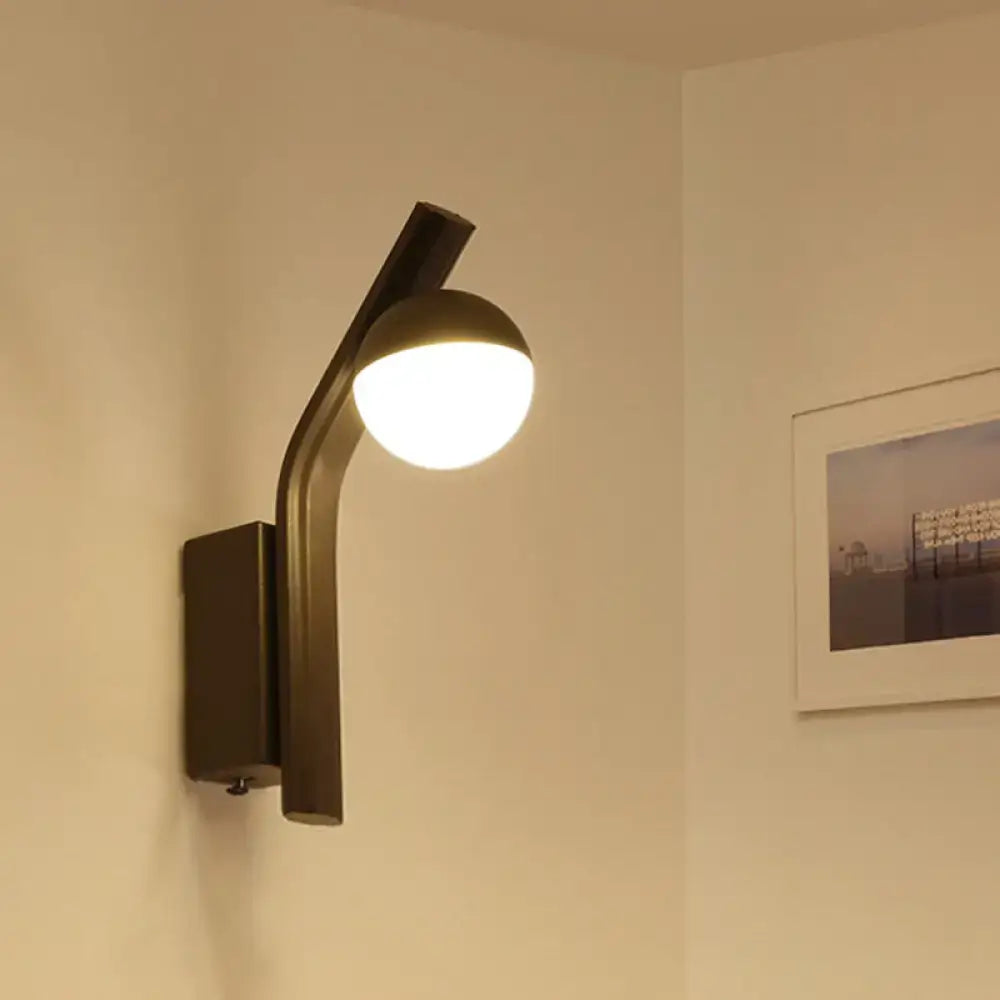 Black glass orb wall sconce with curved matte black metal arm, illuminated on Tampa Home & Garden Store