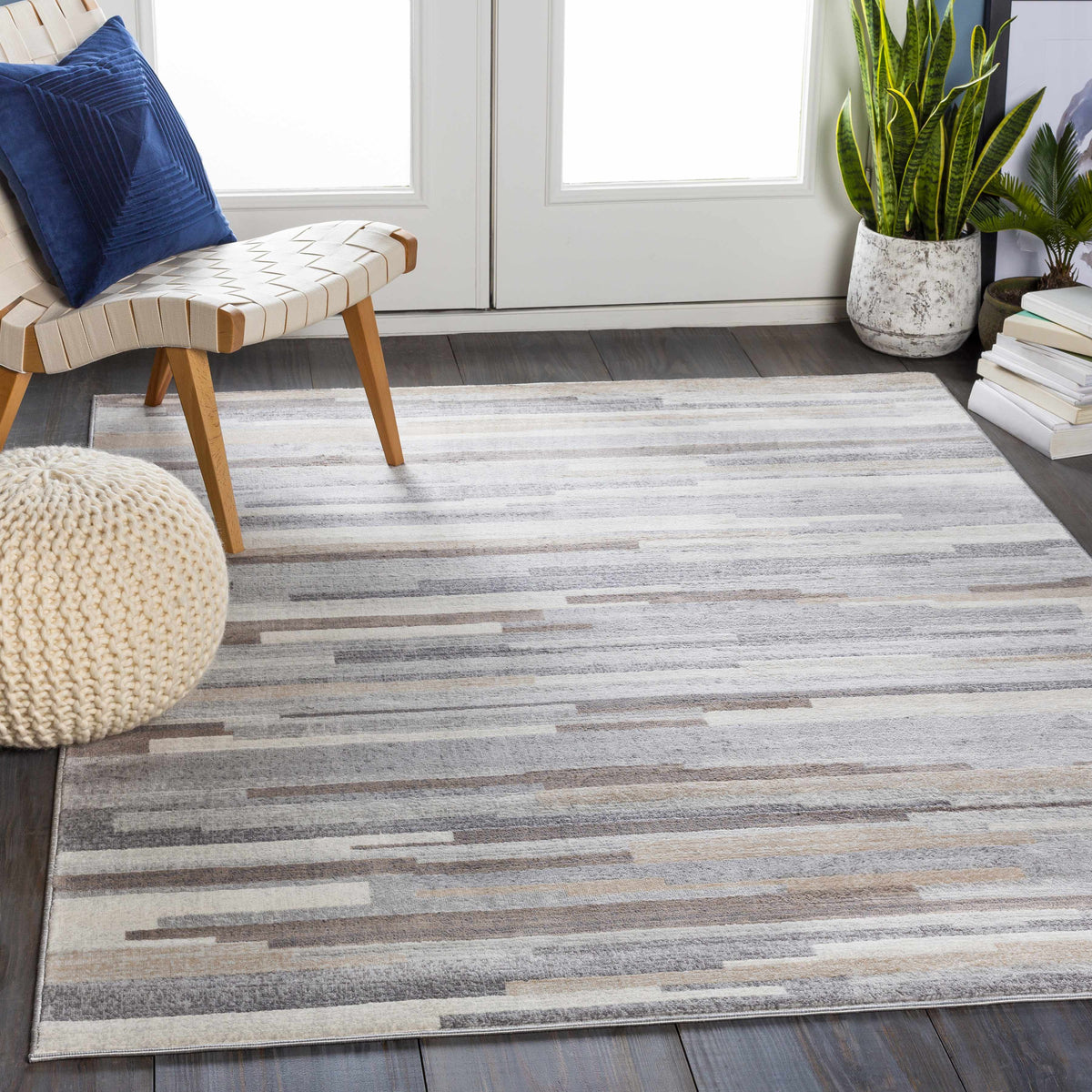 Monkland Area Rug by Boutique Rugs, gray beige striped rug beside a woven chair and two plants on Tampa Home & Garden Store
