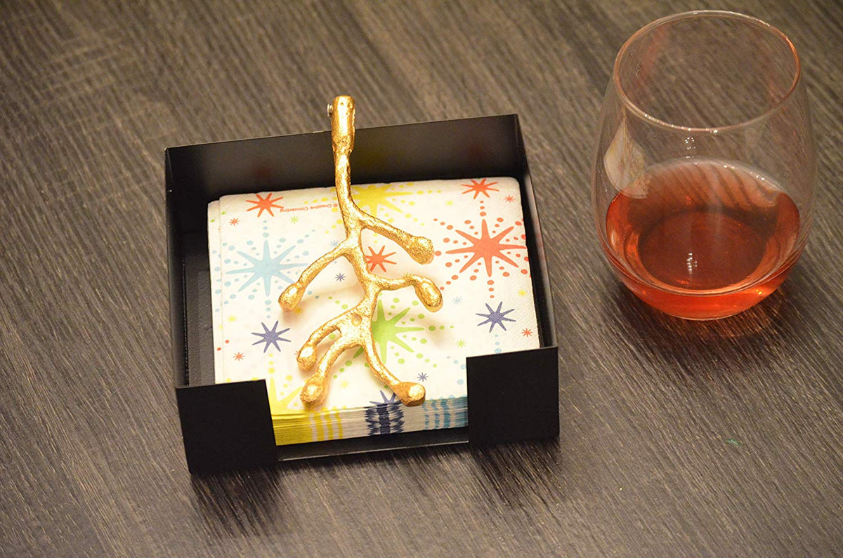 Vibhsa Napkin Holder with gold olive bud in black display box beside starburst napkins on Tampa Home & Garden Store