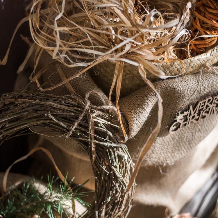 Fall natural rattan and willow wreath beside a Merry Christmas burlap sack on Tampa Home & Garden Store