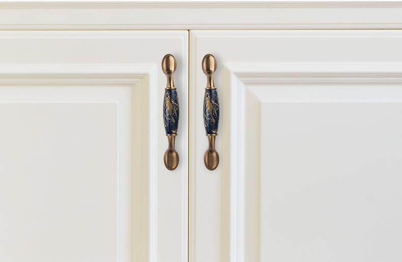 Pair navy blue ceramic cabinet door handles with brass mounts on white kitchen cabinets on Tampa Home & Garden Store
