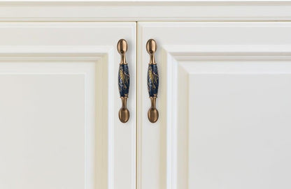 Pair navy blue ceramic cabinet door handles with brass mounts on white kitchen cabinets on Tampa Home & Garden Store