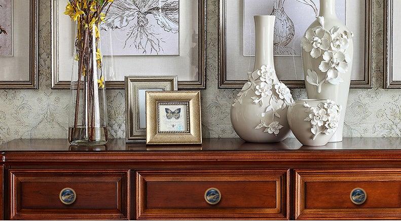 Wooden sideboard with three drawers and round brass knobs, vases and framed art on Tampa Home & Garden Store
