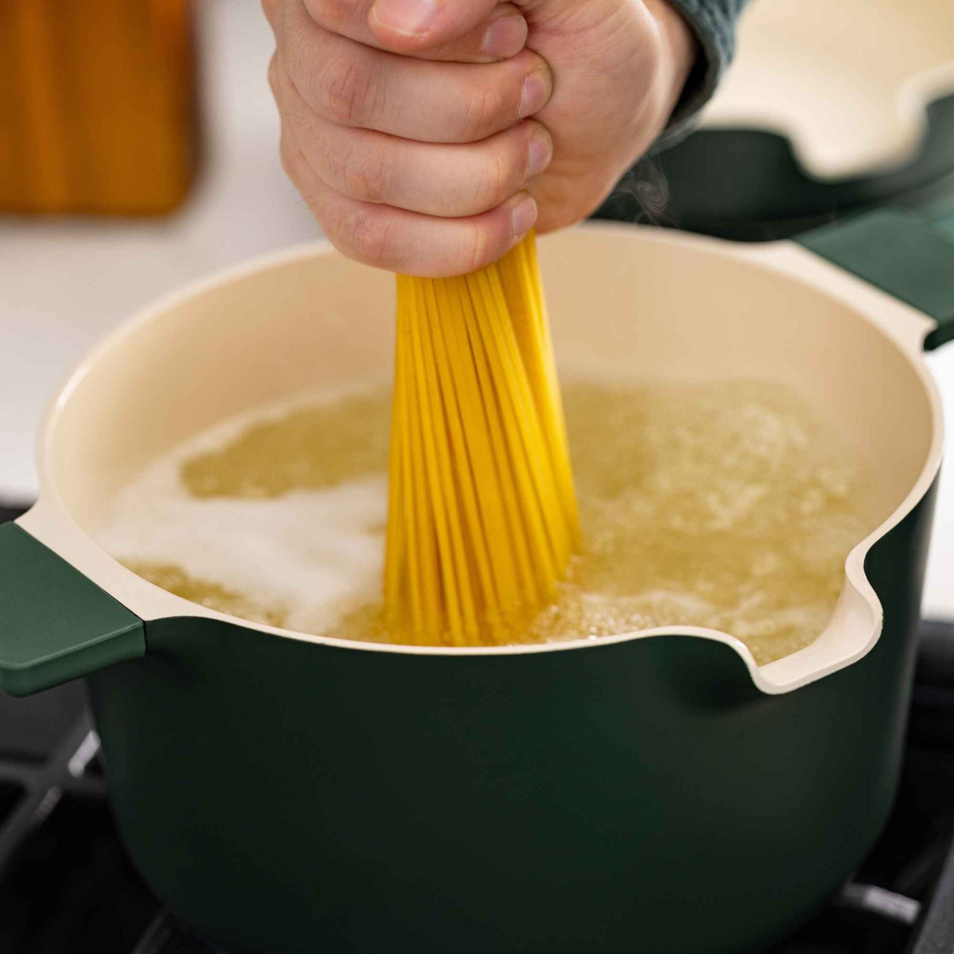 5-Piece Stackable Ceramic Nonstick Cookware Set green exterior cream interior in use boiling pasta on Tampa Home & Garden Store