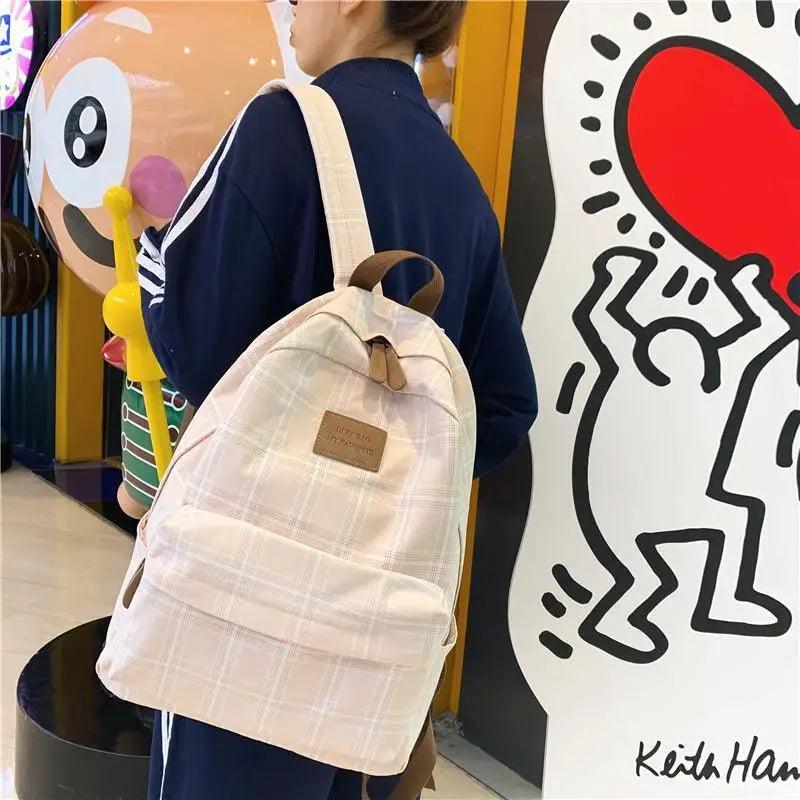 New beige plaid Stevvex school backpack with brown leather patch worn by a woman on Tampa Home & Garden Store