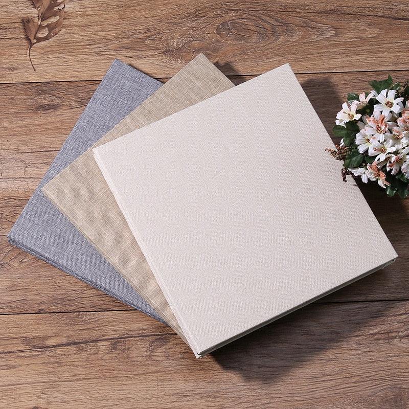Four 16-inch linen DIY photo albums with blue-gray and beige covers on a wood table and bouquet on Tampa Home & Garden Store