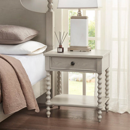 Nightstand with 1 drawer and turned legs in light gray wood finish beside a bed on Tampa Home & Garden Store