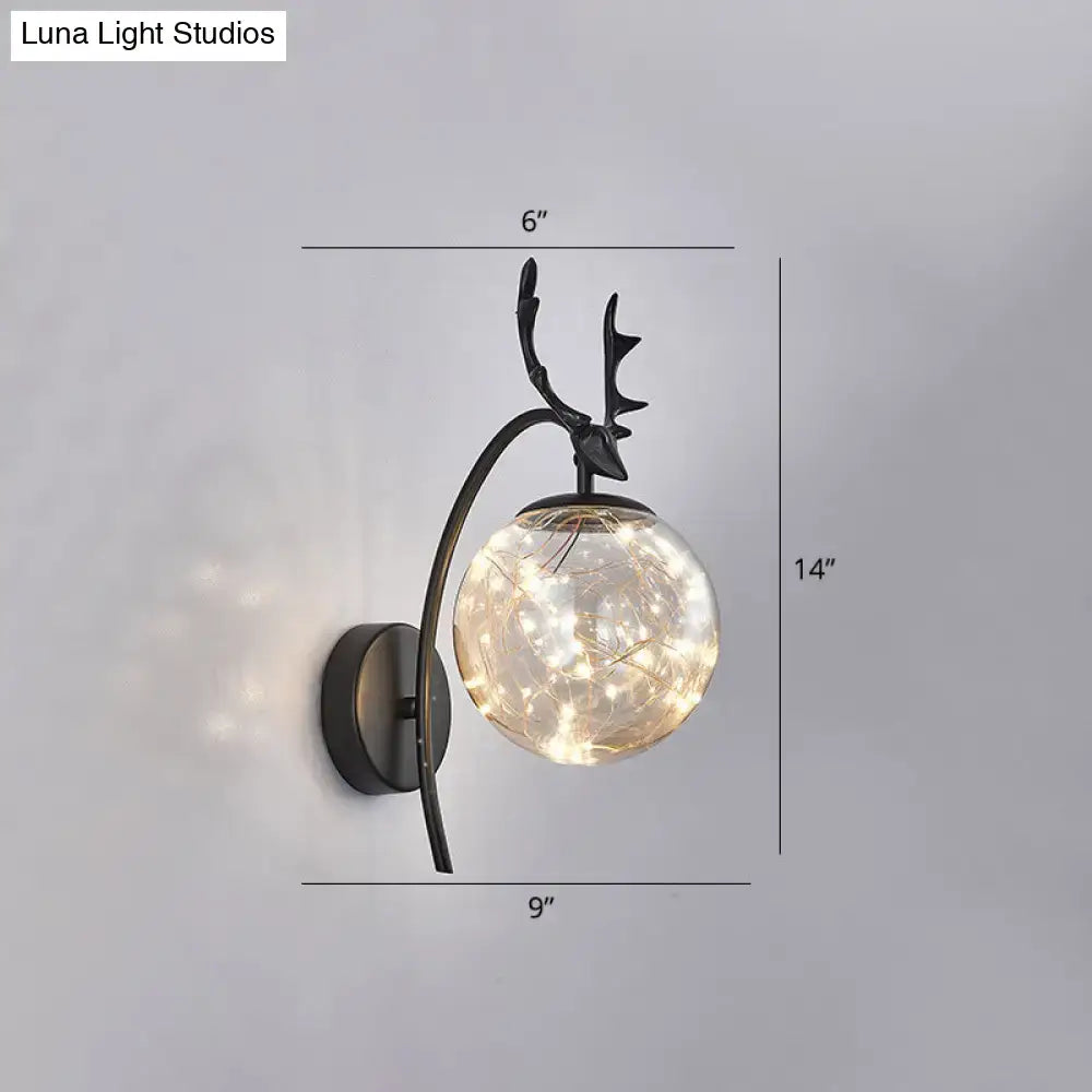 Black antler wall sconce with clear glass globe and warm string lights, wall-mounted on Tampa Home & Garden Store