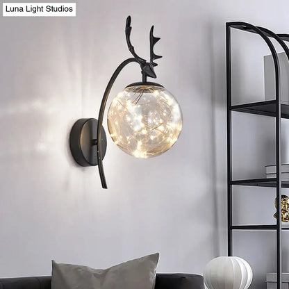 Black Antler Wall Sconce with curved arm and clear glass globe of warm fairy lights on Tampa Home & Garden Store