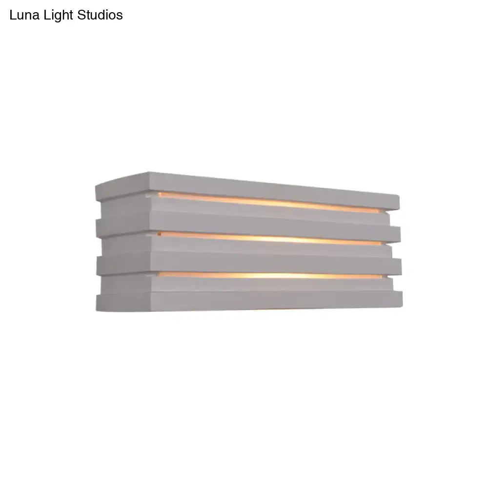 White louvered wall sconce with stacked horizontal slats emitting warm light on Tampa Home & Garden Store