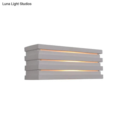 White louvered wall sconce with stacked horizontal slats emitting warm light on Tampa Home & Garden Store