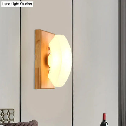 White frosted glass wood-back wall sconce with warm glow on gray wall and nearby wine bottle on Tampa Home & Garden Store