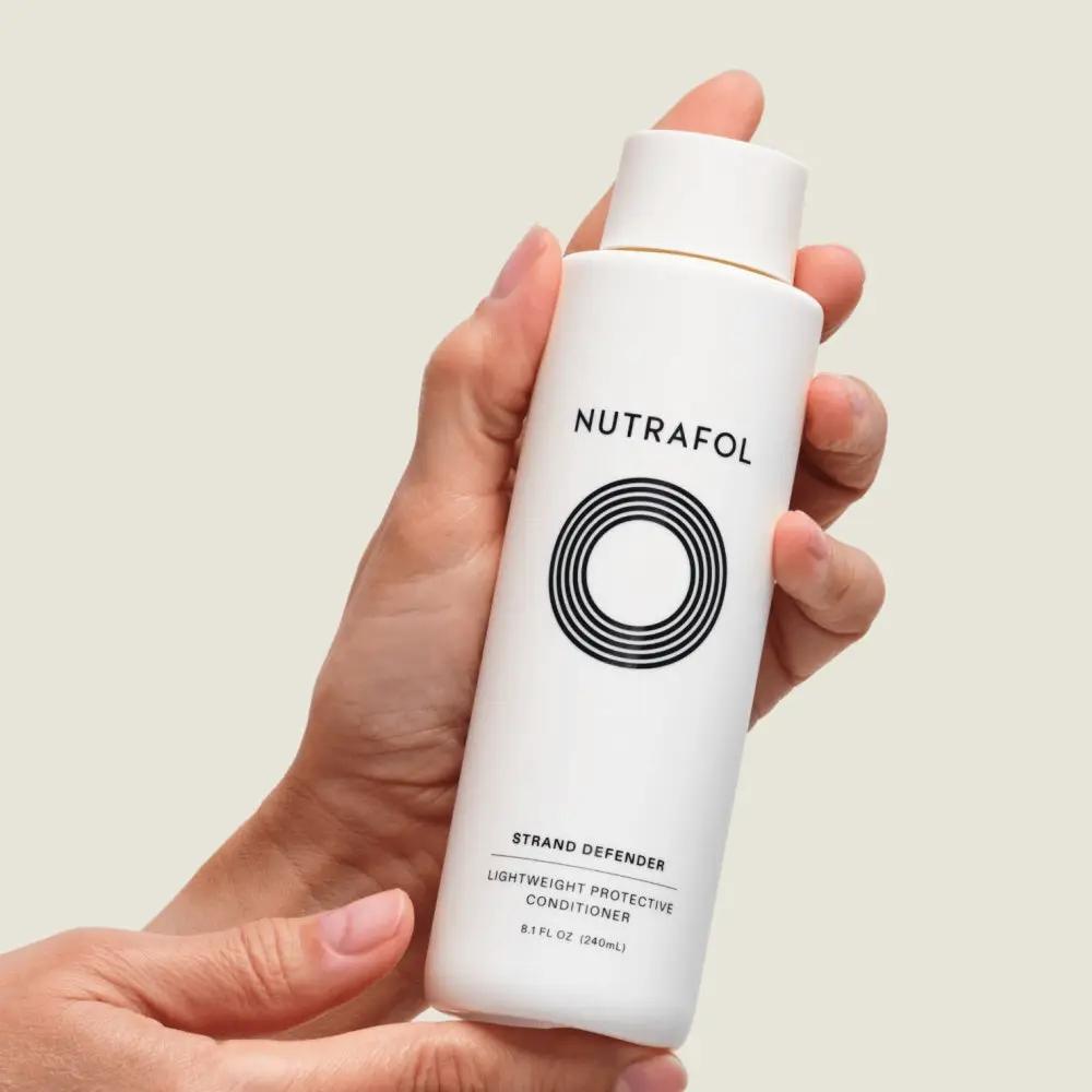 Nutrafol Strand Defender Protective Conditioner white bottle with black logo held in hand on Tampa Home & Garden Store