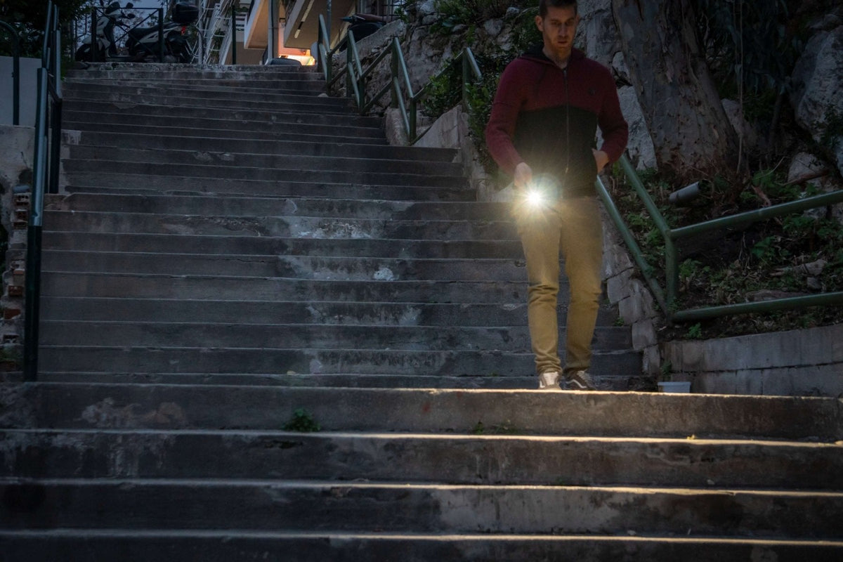 Fenix E08R UE multi-light EDC flashlight held by a man on stairs with bright beam on Tampa Home & Garden Store