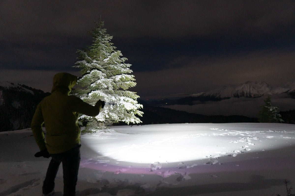 Fenix E08R UE Multi-Light EDC flashlight in use, person in jacket lighting a snowy pine on Tampa Home & Garden Store