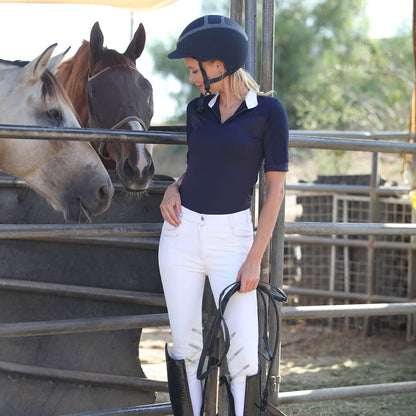 OLIVIA Show Shirt navy polo with white collar worn by rider beside horses in a stable on Tampa Home & Garden Store