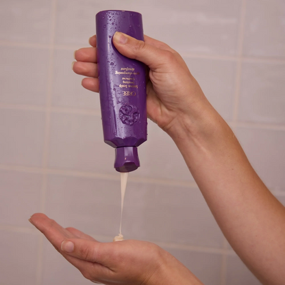 Oribe Serene Scalp Densifying Conditioner bottle squeezed into hand, purple bottle on Tampa Home & Garden Store