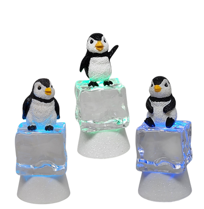 Five penguin figurines perched on frosty ice cube bases with color-changing LED lighting on Tampa Home & Garden Store