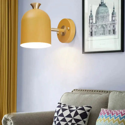 Mustard yellow macaron-style wall sconce lamp with brass accents beside framed print over sofa on Tampa Home & Garden Store
