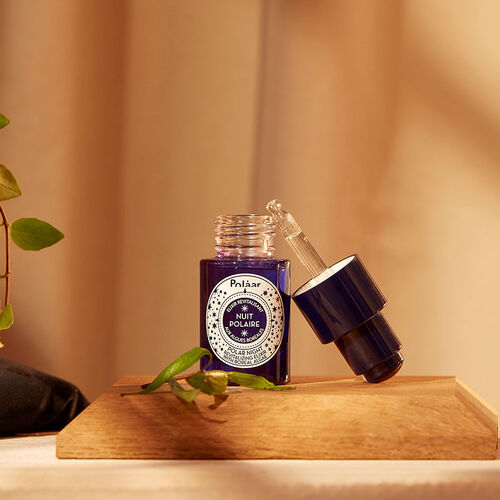 Polaar Night Revitalizing Elixir Glow Serum bottle in purple glass with dropper on a wooden stand on Tampa Home & Garden Store