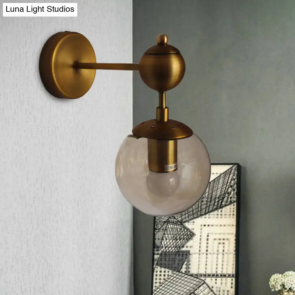 Brass amber globe wall sconce with clear glass orb, round backplate and brass accents on Tampa Home & Garden Store