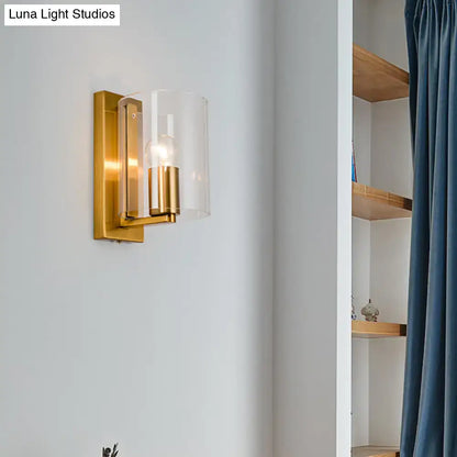 Brass finish clear glass wall sconce with cylindrical shade and exposed bulb on Tampa Home & Garden Store