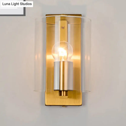Brass clear-glass sconce by Decorbites with cylindrical glass shade and warm glow on Tampa Home & Garden Store