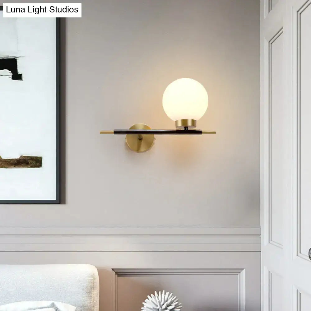 Decorbites White brass sphere sconce with frosted globe on black bar and brass mount on Tampa Home & Garden Store