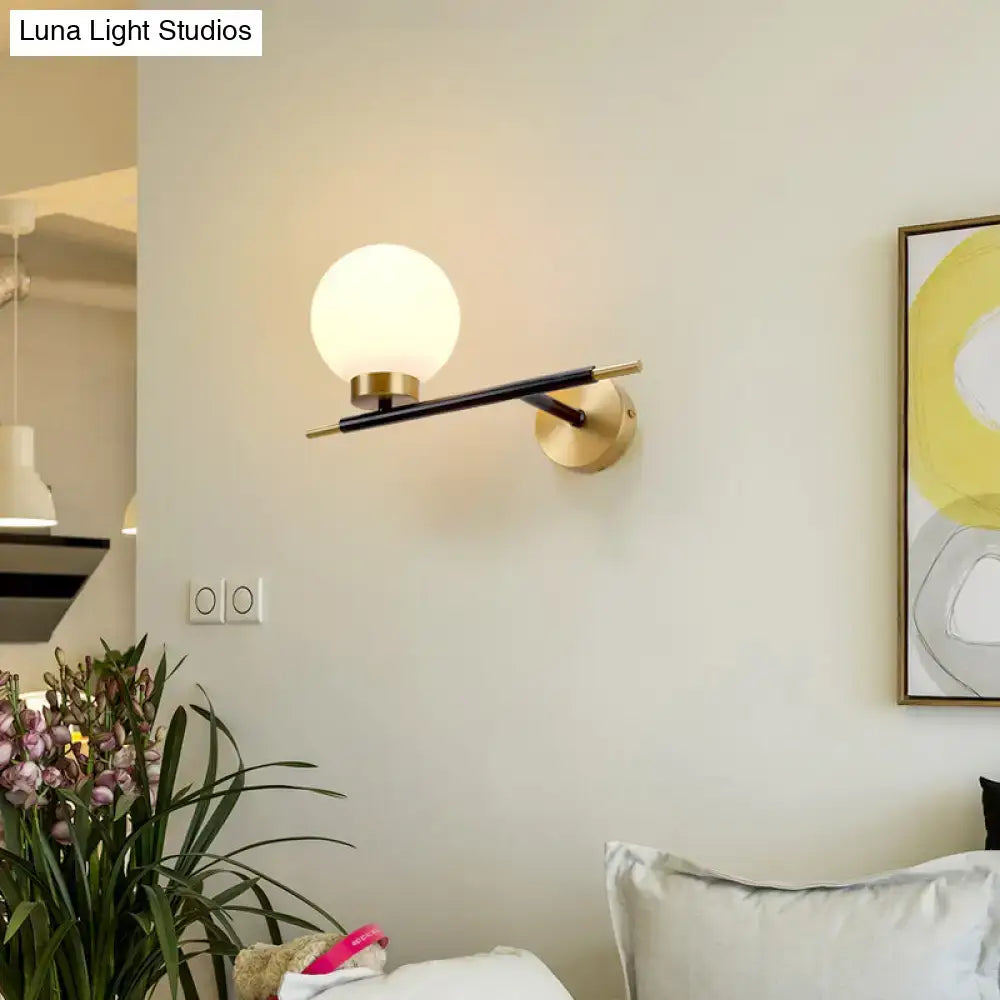White brass sphere sconce by Decorbites with frosted globe and black metal arm on wall mount on Tampa Home & Garden Store