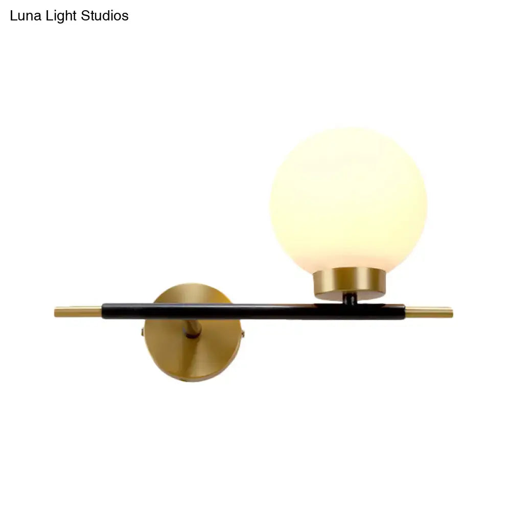 White brass sphere sconce with frosted glass globe set on a black brass wall bar on Tampa Home & Garden Store
