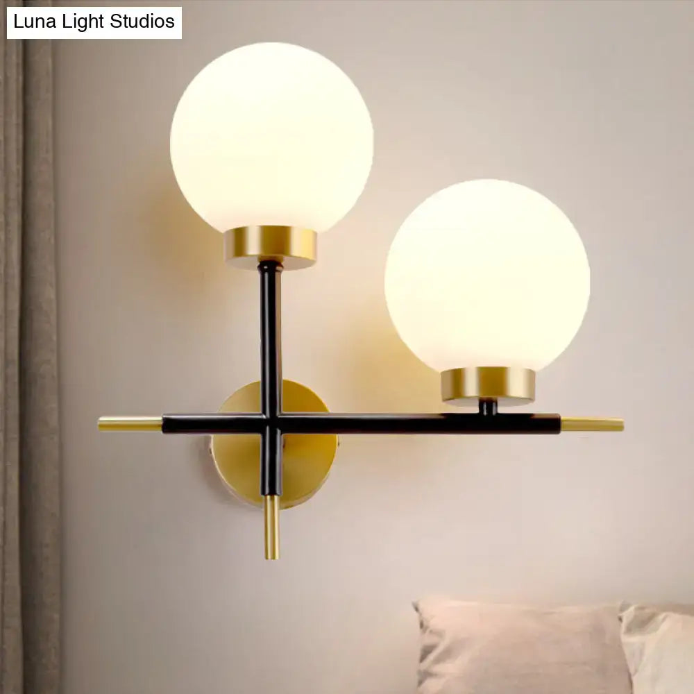 White brass sphere sconce with two frosted globes on black metal cross, brass accents Decorbites on Tampa Home & Garden Store