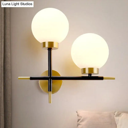 White brass sphere sconce with two frosted globes on black metal cross, brass accents Decorbites on Tampa Home & Garden Store