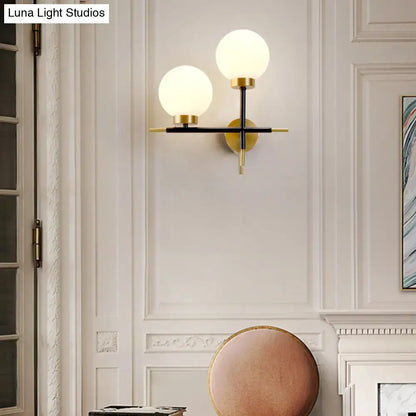 White Brass Sphere Sconce with dual frosted globes on a black cross wall mount on Tampa Home & Garden Store