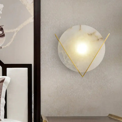White marble wall sconce by Decorbites with circular backplate and gold V arms, warm glow on Tampa Home & Garden Store