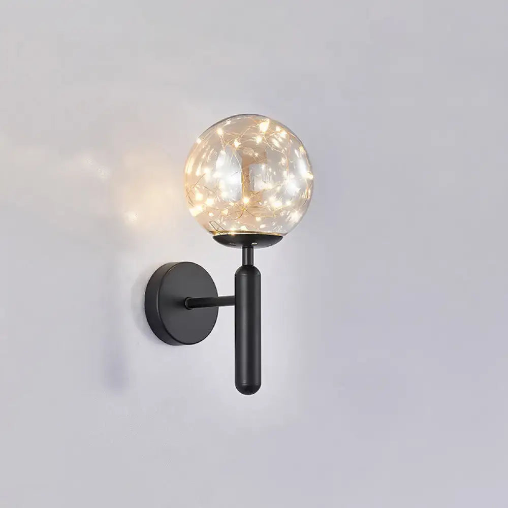Black glass wall sconce with clear spherical globe and warm string lights, black metal arm on Tampa Home & Garden Store