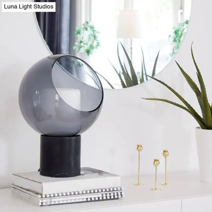 Black Marble Table Lamp with smoky gray glass globe on a black pedestal atop books on Tampa Home & Garden Store