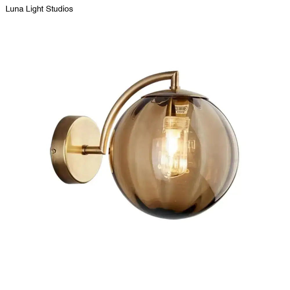 Decorbites Brass Amber Ball Sconce with curved brass arm and amber glass globe on Tampa Home & Garden Store