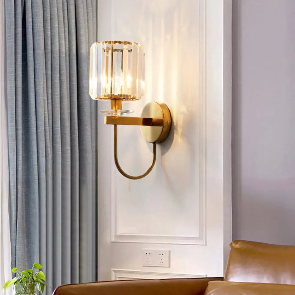 Gold crystal curved-arm wall sconce with faceted glass shade on a white paneled wall on Tampa Home & Garden Store