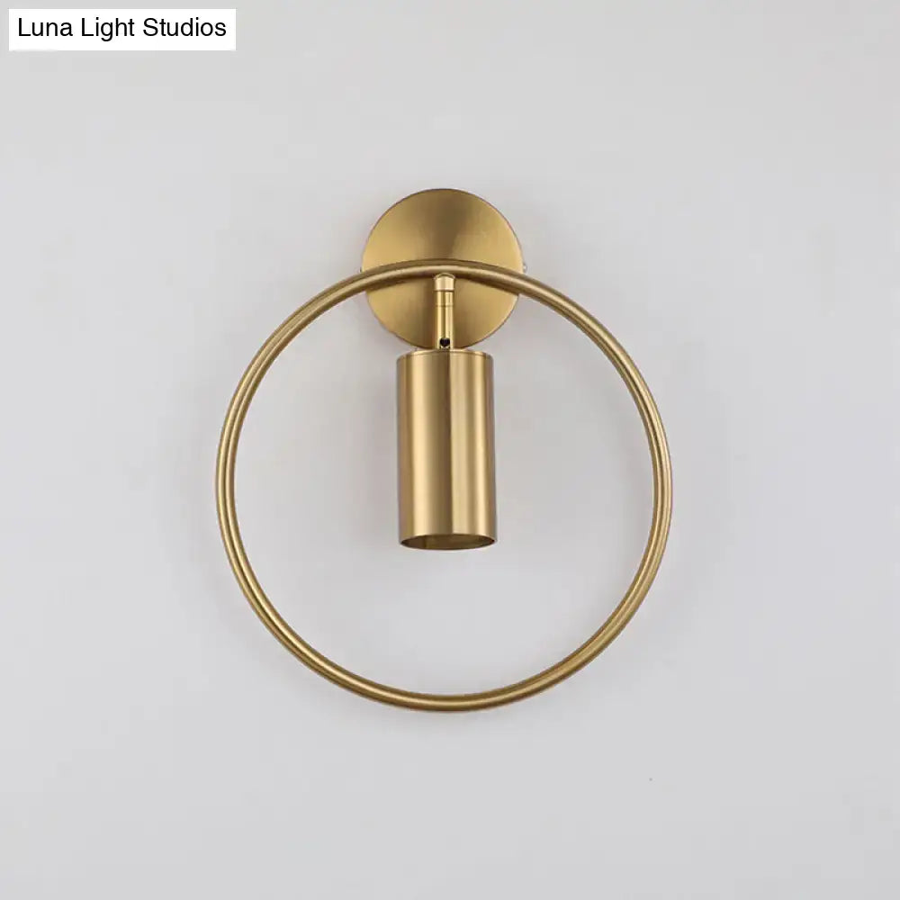 Gold halo ring wall sconce with vertical cylindrical light against a round backplate on Tampa Home & Garden Store