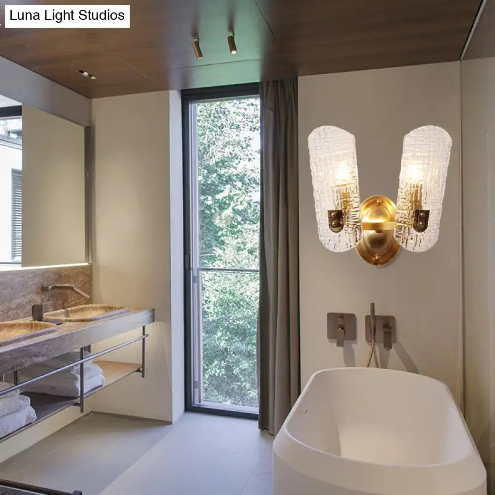 Gold prism glass sconce with twin textured shades on brass above a white tub in a bathroom on Tampa Home & Garden Store