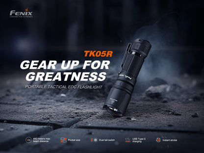 Fenix TK05R tactical EDC flashlight black aluminum with pocket clip angled on rocky ground on Tampa Home & Garden Store