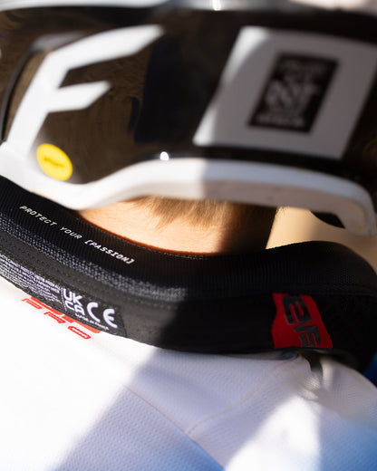 2026 R2 Race Collar neck brace by EVS Sports; black strap with red logo under a white helmet on Tampa Home & Garden Store