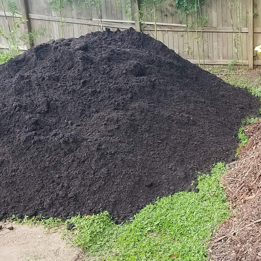 Two piles of compost, one dark and one brown, in a garden setting.