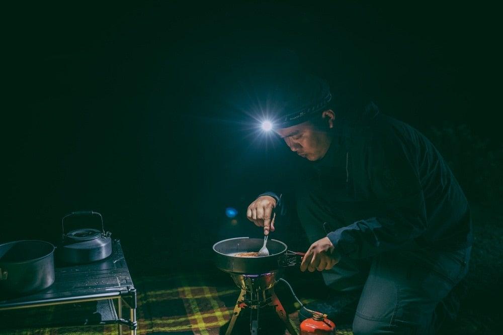 Headlamp by Stevvex, rechargeable high-lumen LED worn by camper cooking at night on Tampa Home & Garden Store