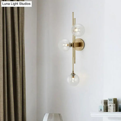 Brass triple globe sconce with clear glass globes on vertical rod wall mount on Tampa Home & Garden Store